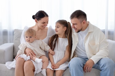 Photo of Happy parents and their kids together on sofa at home