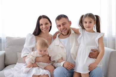 Photo of Happy parents and their kids together on sofa at home