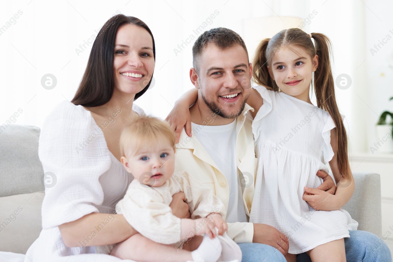 Happy parents and their kids together on sofa at home Photo of Happy parents and their kids together on sofa at home