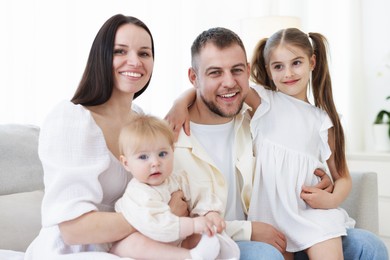 Photo of Happy parents and their kids together on sofa at home
