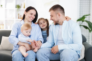 Photo of Happy parents and their kids together on sofa at home