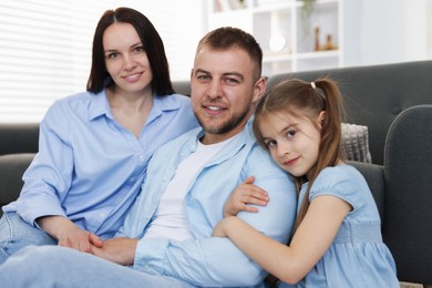 Photo of Happy parents and their daughter together on sofa at home