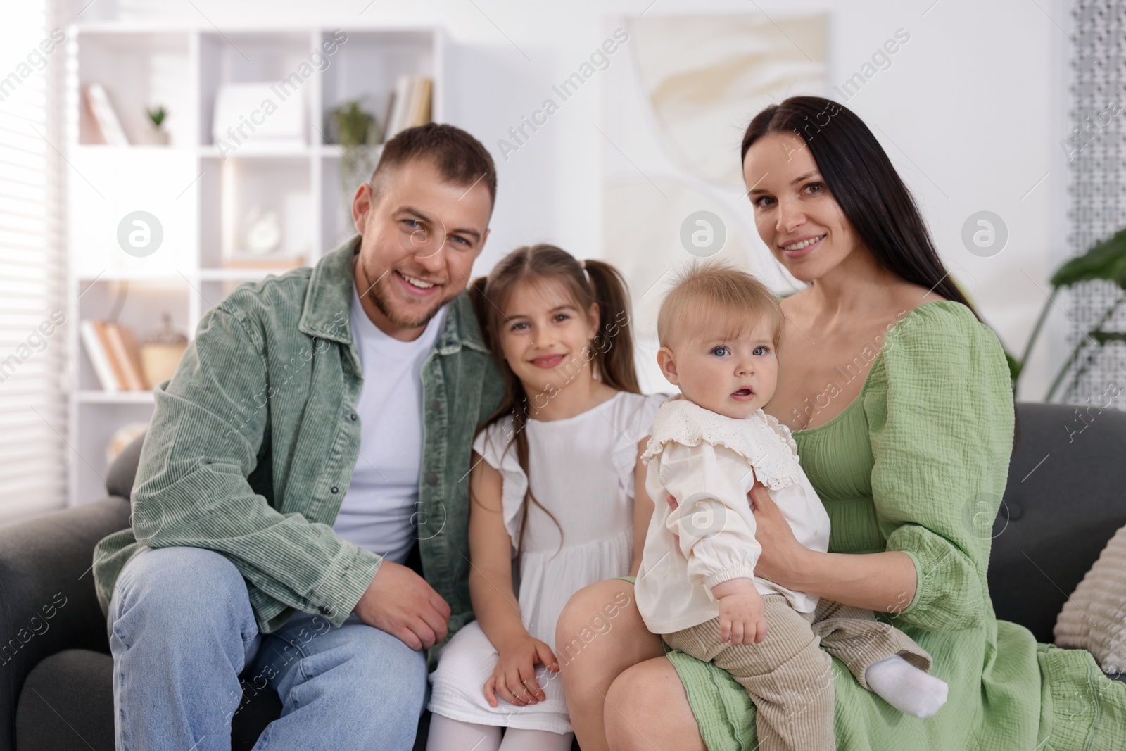 Happy parents and their kids together on sofa at home Photo of Happy parents and their kids together on sofa at home