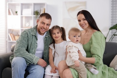 Photo of Happy parents and their kids together on sofa at home