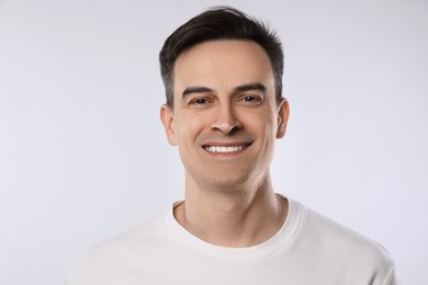 Photo of Portrait of smiling man on light grey background, closeup