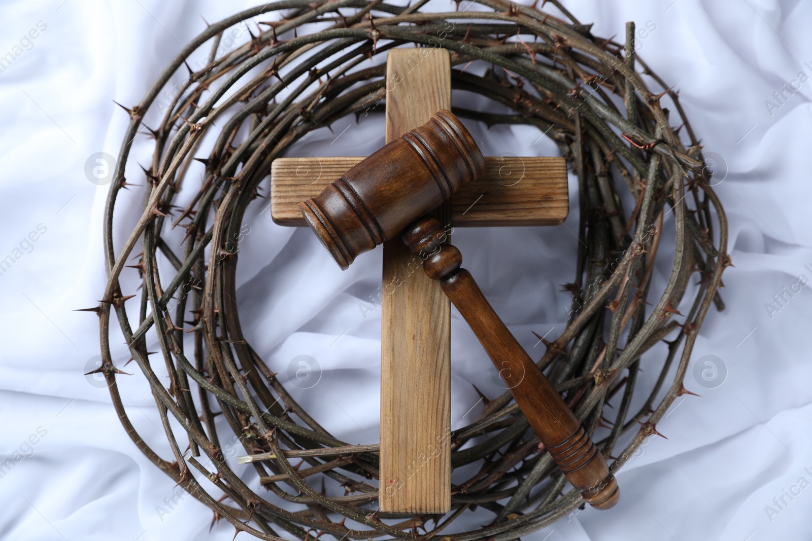Judge's gavel, crown of thorns and wooden cross on white fabric, top view Photo of Judge's gavel, crown of thorns and wooden cross on white fabric, top view