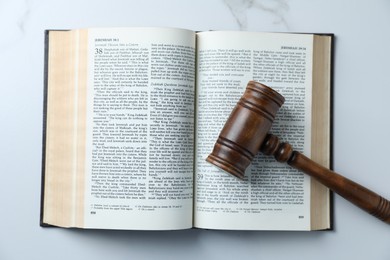 Photo of Judge's gavel and Bible on white marble table, top view