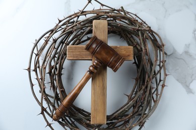 Photo of Judge's gavel, wooden cross and crown of thorns on white marble table, top view