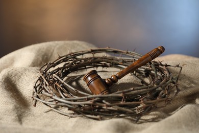 Photo of Judge's gavel and crown of thorns on burlap fabric, closeup