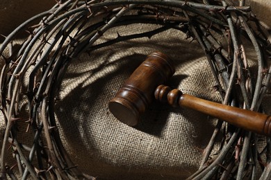 Photo of Judge's gavel and crown of thorns on burlap fabric, above view