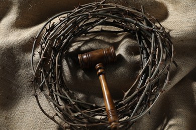 Photo of Judge's gavel and crown of thorns on burlap fabric, above view