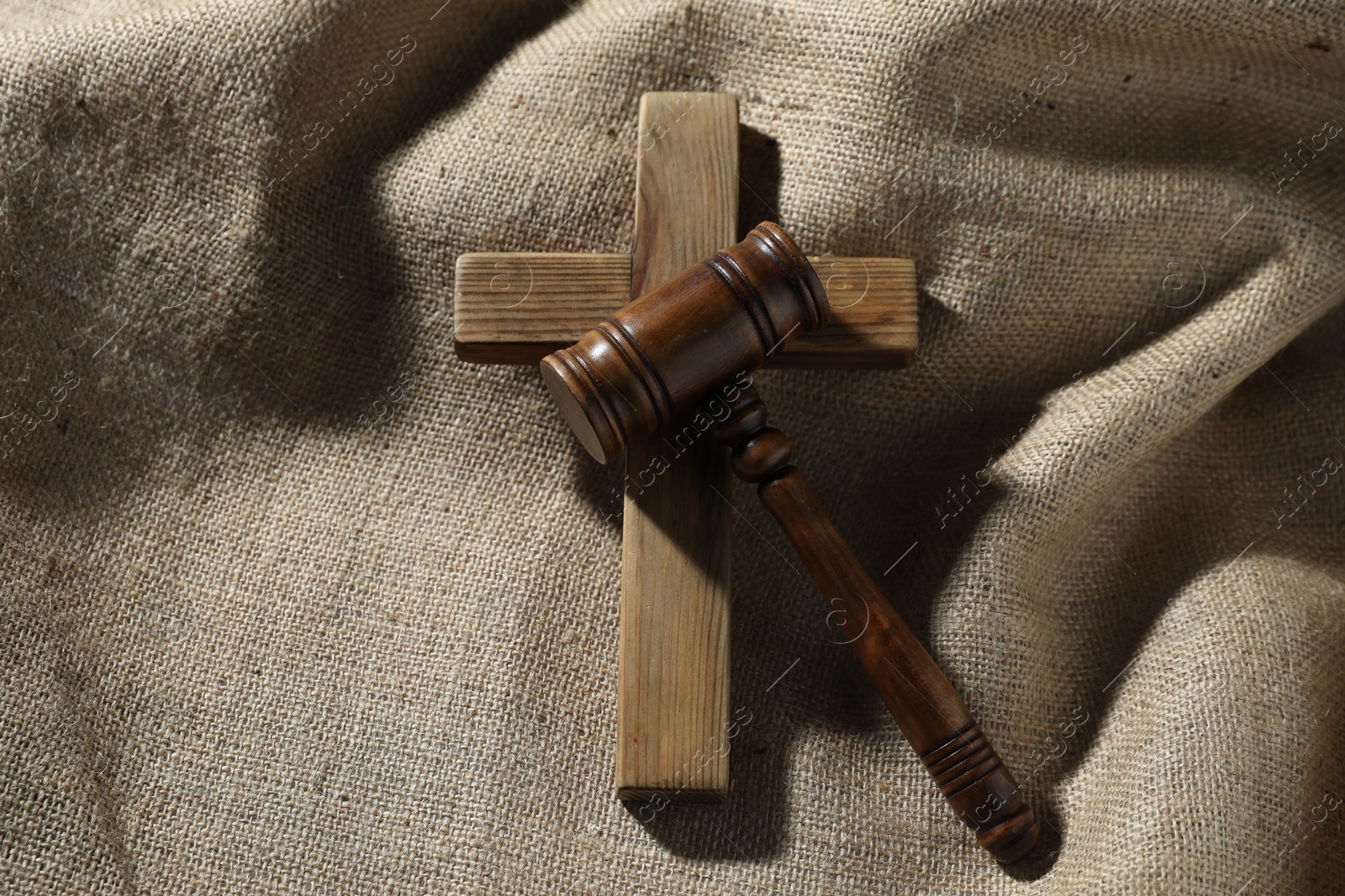 Judge's gavel and wooden cross on burlap fabric, top view Photo of Judge's gavel and wooden cross on burlap fabric, top view