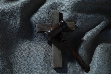 Photo of Judge's gavel and wooden cross on burlap fabric, top view