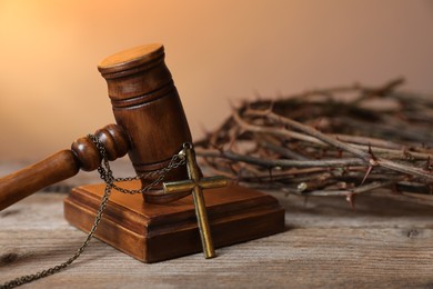 Photo of Judge's gavel with cross and crown of thorns on wooden table, closeup