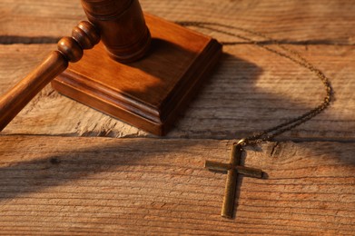 Photo of Judge's gavel and cross on wooden table, above view