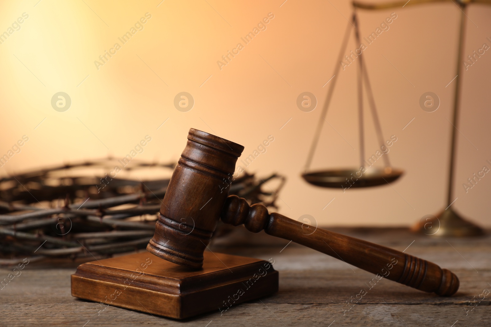Judge's gavel, crown of thorns and scales on wooden table against pale orange gradient background, closeup Photo of Judge's gavel, crown of thorns and scales on wooden table against pale orange gradient background, closeup