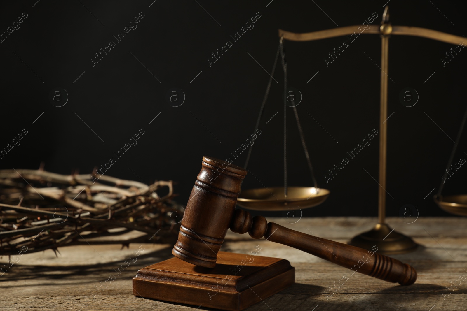 Judge's gavel, scales and crown of thorns on wooden table against black background, closeup Photo of Judge's gavel, scales and crown of thorns on wooden table against black background, closeup