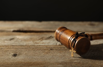 Photo of Judge's gavel and cross on wooden table, closeup. Space for text