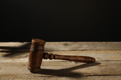 Photo of Judge's gavel on wooden table against black background