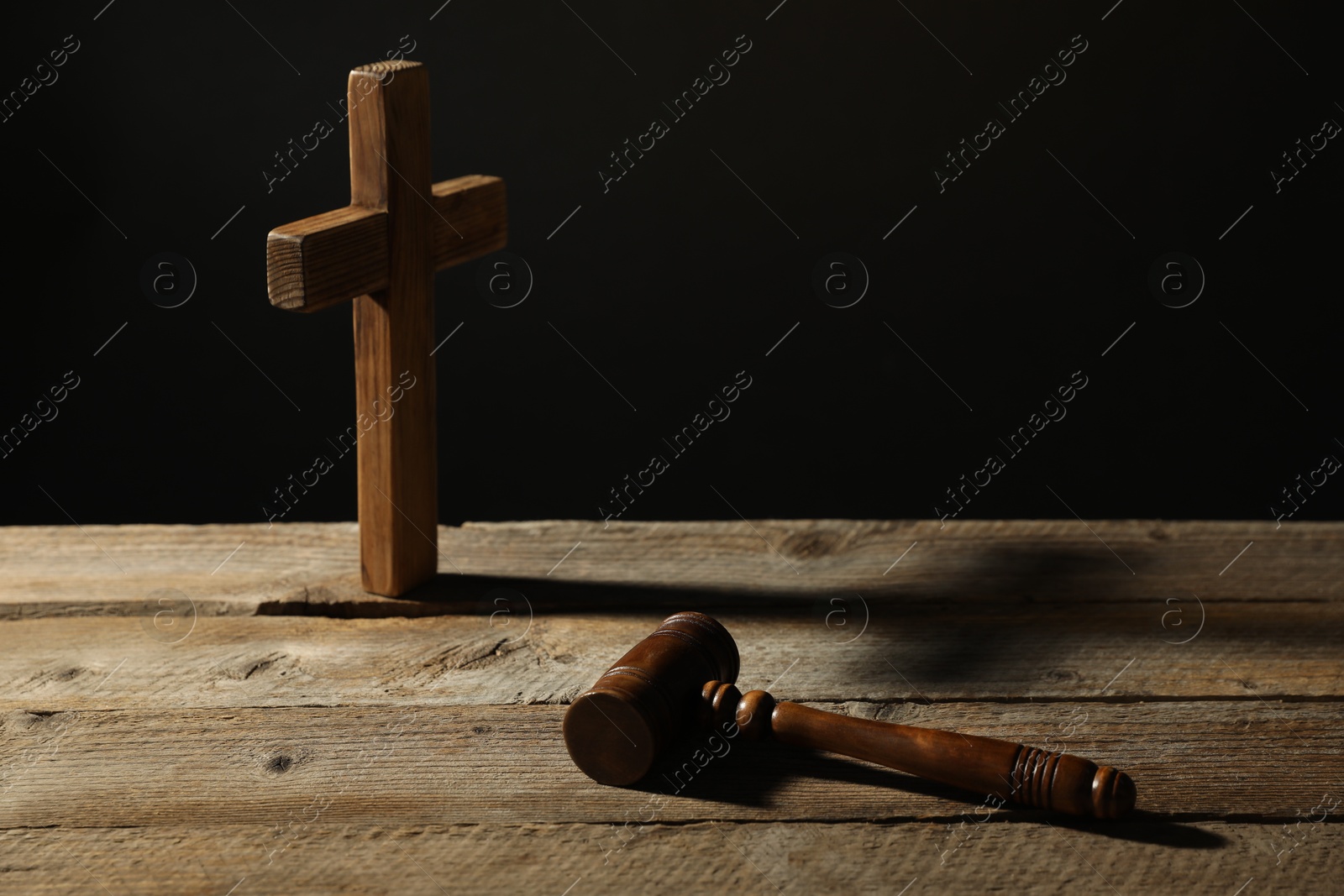Judge's gavel and cross on wooden table against black background Photo of Judge's gavel and cross on wooden table against black background
