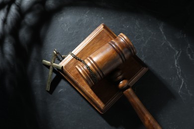 Photo of Judge's gavel and cross on black table, top view
