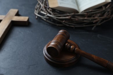 Photo of Judge's gavel, crown of thorns, Bible and wooden cross on black table, closeup