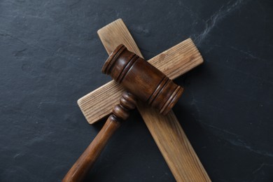 Photo of Judge's gavel and wooden cross on black table, top view