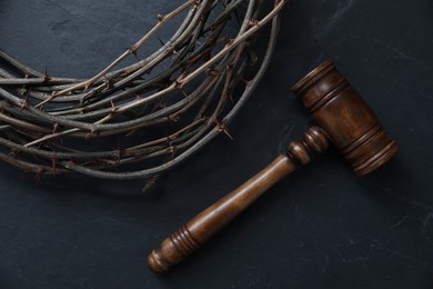 Photo of Judge's gavel and crown of thorns on black table, flat lay