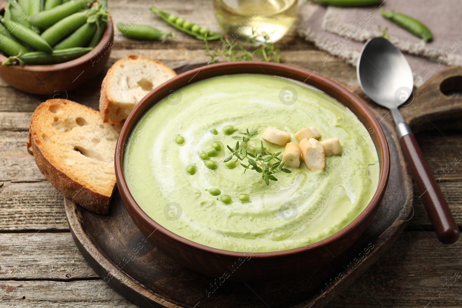 Tasty pea cream soup with croutons and thyme served on wooden table, closeup Photo of Tasty pea cream soup with croutons and thyme served on wooden table, closeup