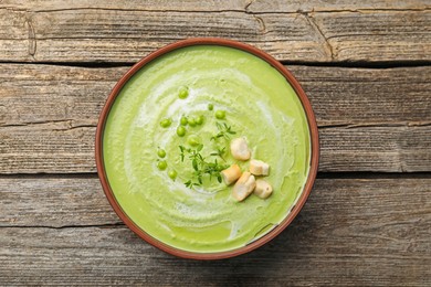 Photo of Tasty pea cream soup with croutons and thyme on wooden table, top view