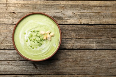 Photo of Tasty pea cream soup with croutons and thyme on wooden table, top view. Space for text