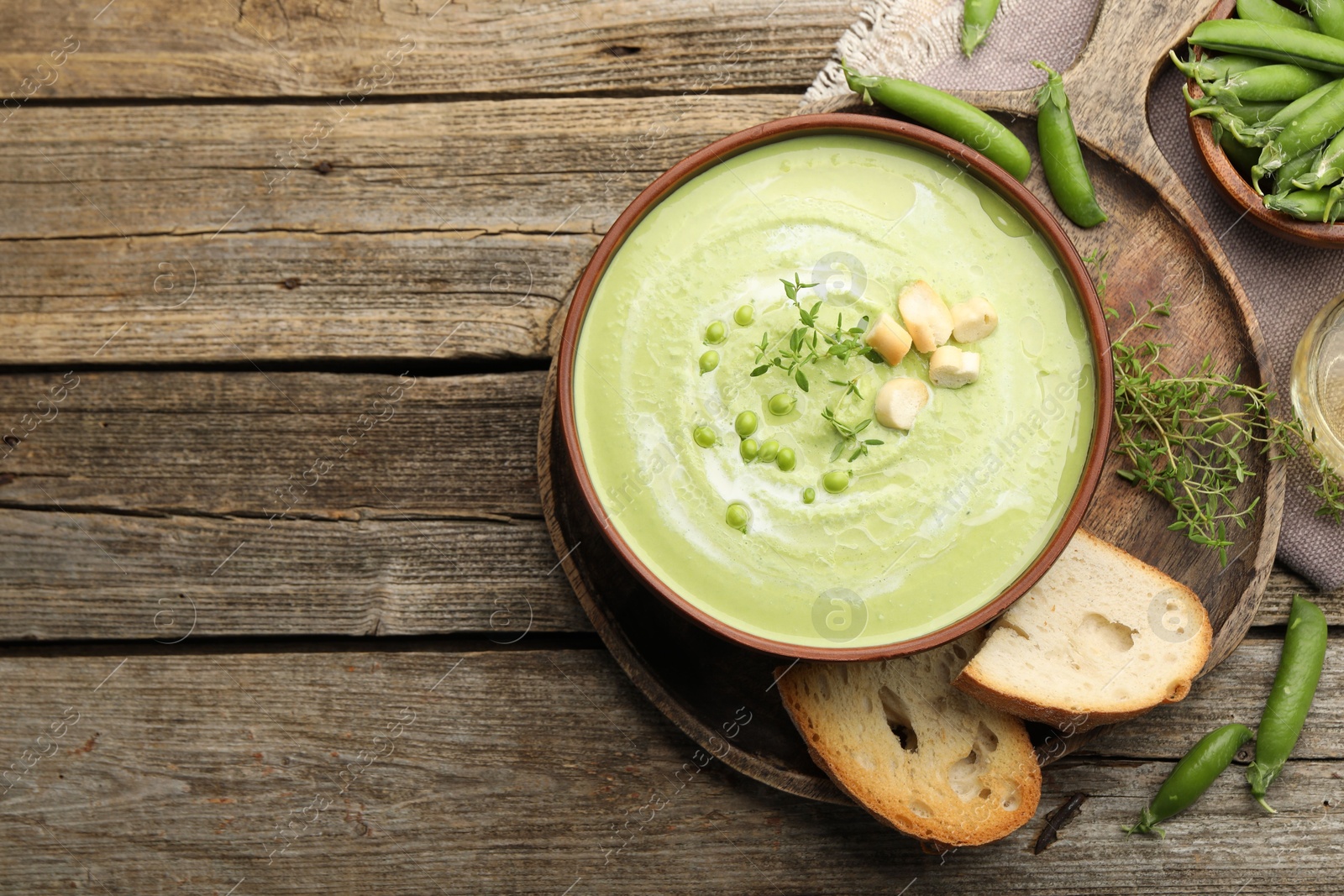 Tasty pea cream soup with croutons and thyme served on wooden table, flat lay. Space for text Photo of Tasty pea cream soup with croutons and thyme served on wooden table, flat lay. Space for text