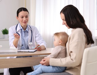 Photo of Mother and her cute baby having appointment with pediatrician in clinic