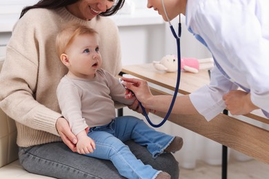 Photo of Pediatrician examining baby with stethoscope in clinic, closeup