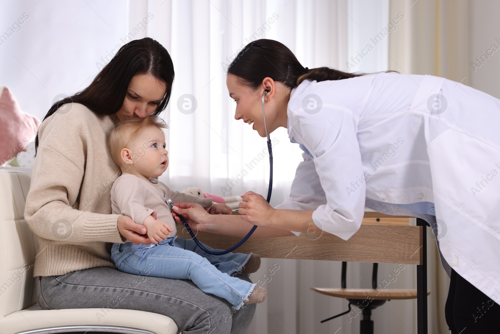 Pediatrician examining baby with stethoscope in clinic Photo of Pediatrician examining baby with stethoscope in clinic