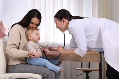Photo of Pediatrician examining baby with stethoscope in clinic