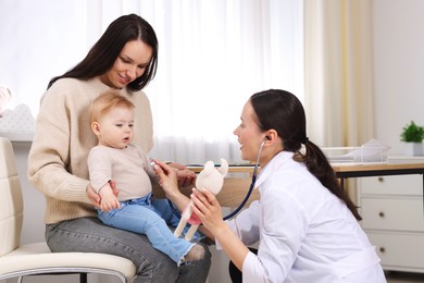 Photo of Pediatrician examining baby with stethoscope in clinic