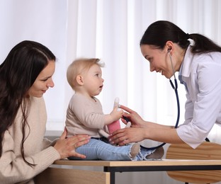 Photo of Pediatrician examining baby with stethoscope in clinic