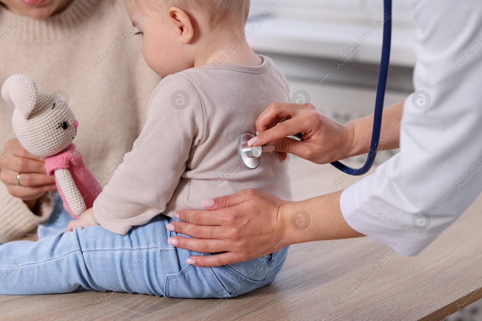 Pediatrician examining baby with stethoscope in clinic, closeup Photo of Pediatrician examining baby with stethoscope in clinic, closeup