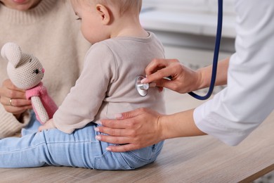 Photo of Pediatrician examining baby with stethoscope in clinic, closeup