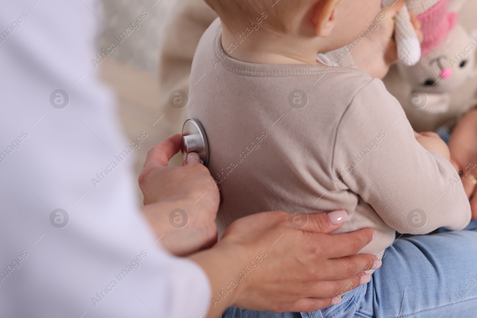 Pediatrician examining baby with stethoscope in clinic, closeup Photo of Pediatrician examining baby with stethoscope in clinic, closeup