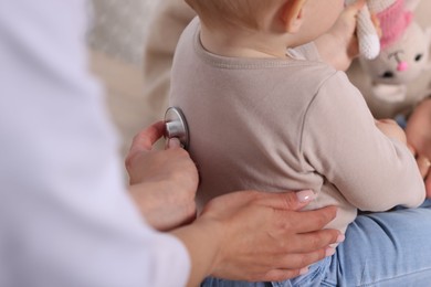 Photo of Pediatrician examining baby with stethoscope in clinic, closeup