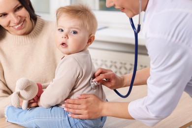 Photo of Pediatrician examining baby with stethoscope in clinic, closeup