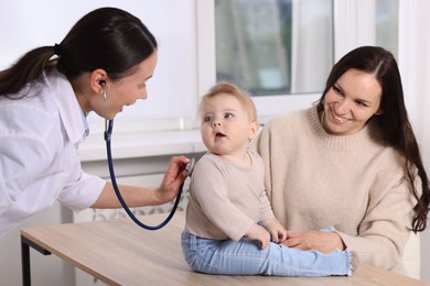 Photo of Pediatrician examining baby with stethoscope in clinic