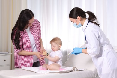 Photo of Mother and her cute baby having appointment with pediatrician in clinic. Doctor vaccinating child