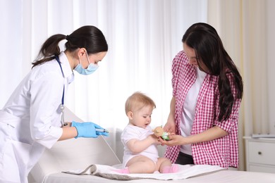 Photo of Mother and her cute baby having appointment with pediatrician in clinic. Doctor vaccinating child