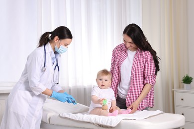 Photo of Mother and her cute baby having appointment with pediatrician in clinic. Doctor vaccinating child
