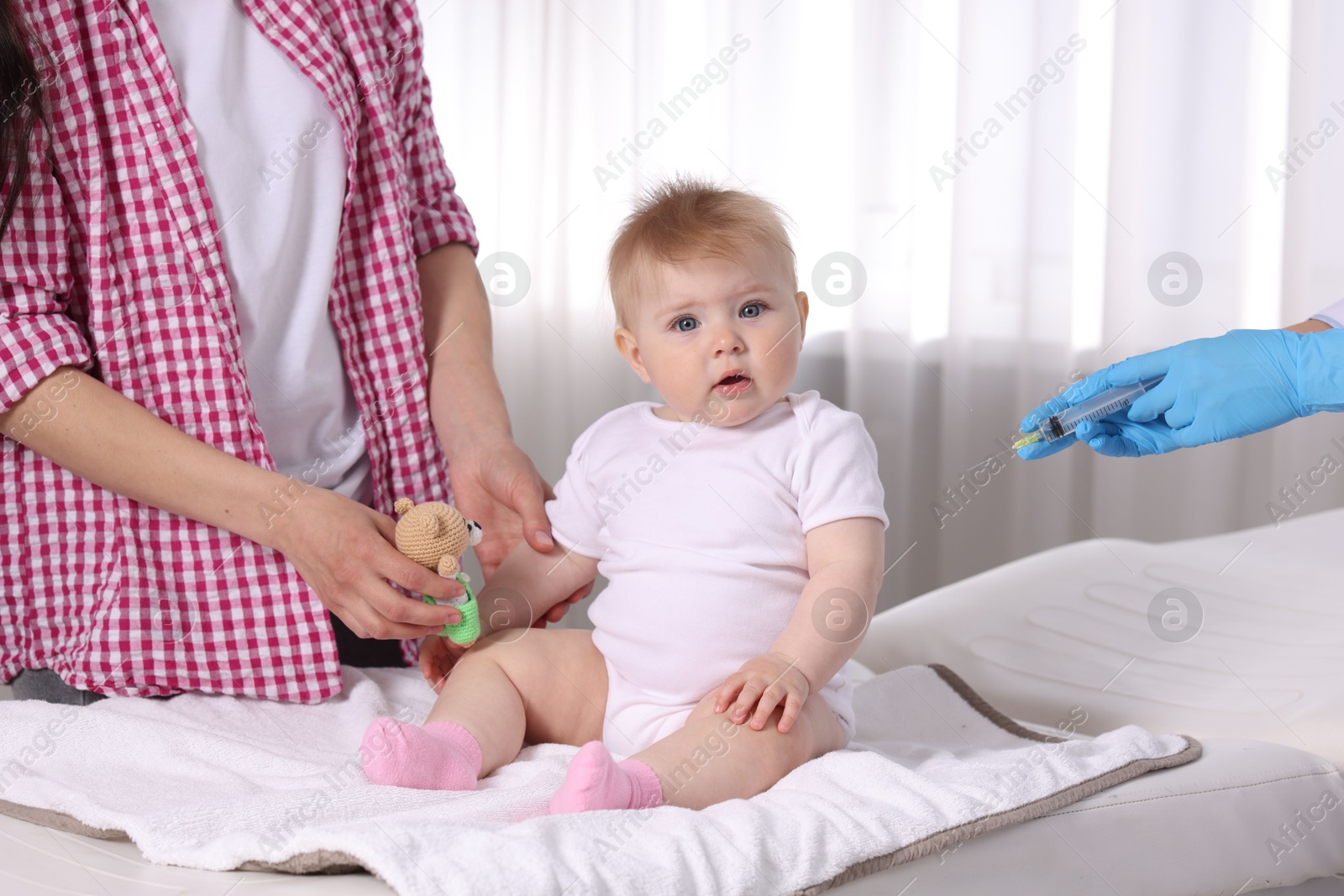 Mother and her cute baby having appointment with pediatrician in clinic, closeup. Doctor vaccinating child Photo of Mother and her cute baby having appointment with pediatrician in clinic, closeup. Doctor vaccinating child