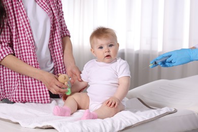 Photo of Mother and her cute baby having appointment with pediatrician in clinic, closeup. Doctor vaccinating child
