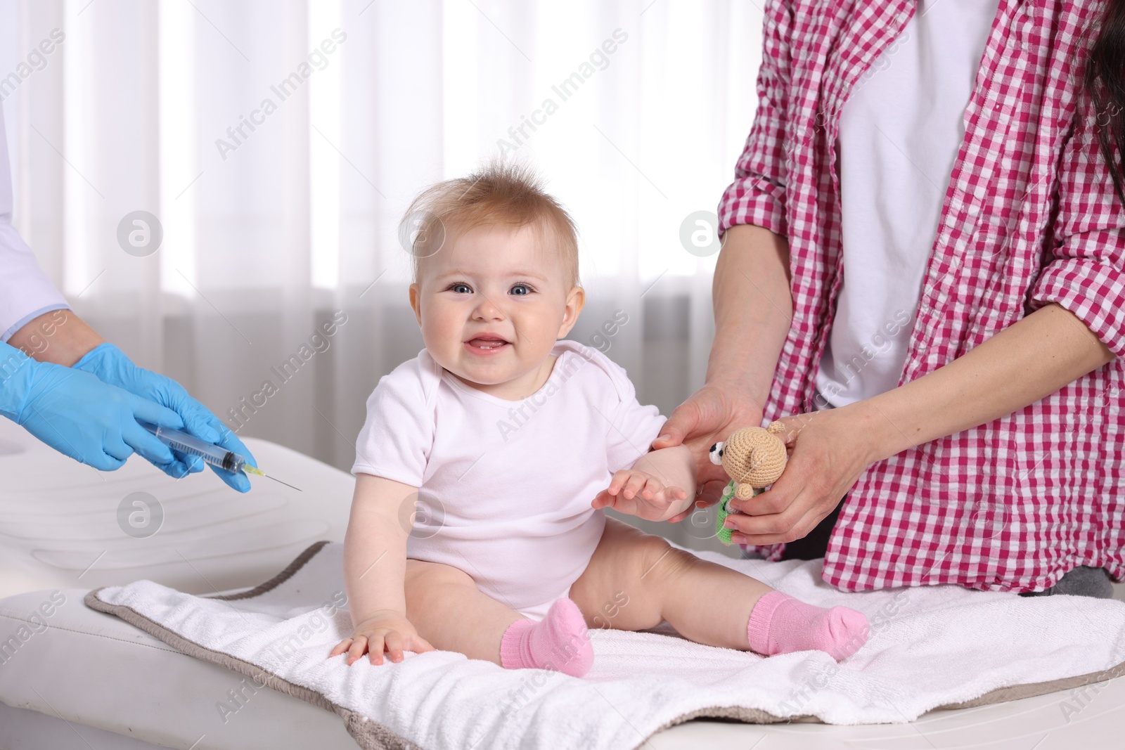 Mother and her cute baby having appointment with pediatrician in clinic, closeup. Doctor vaccinating child Photo of Mother and her cute baby having appointment with pediatrician in clinic, closeup. Doctor vaccinating child